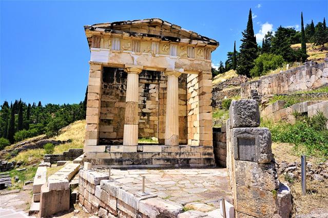 The Athenian Treasury at Delphi, an ancient Greek temple with Doric columns representing foundational economic models.